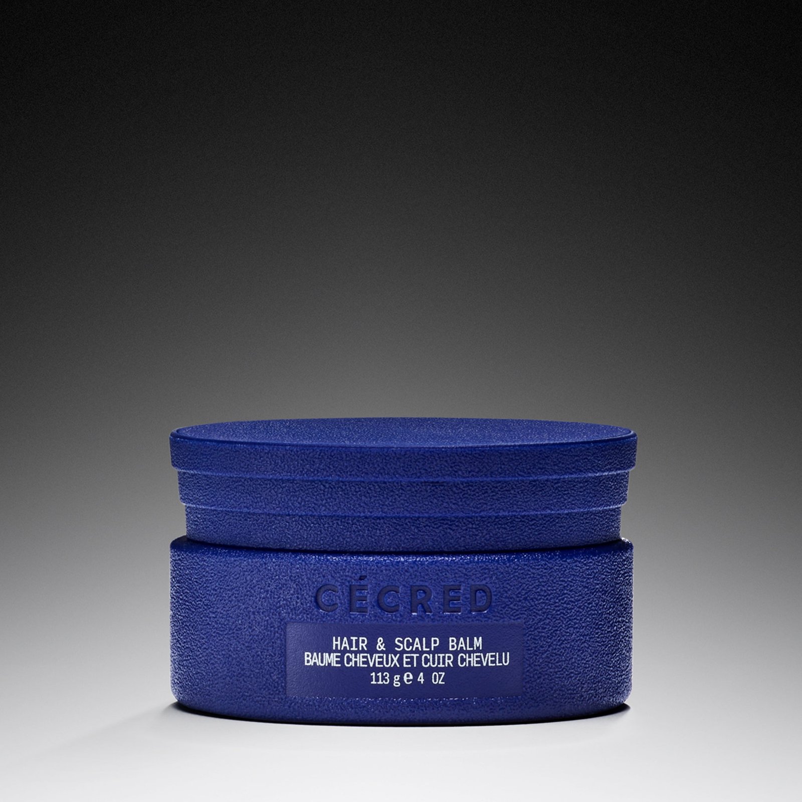 Cécred Hair & Scalp Balm in a blue jar on a gradient background