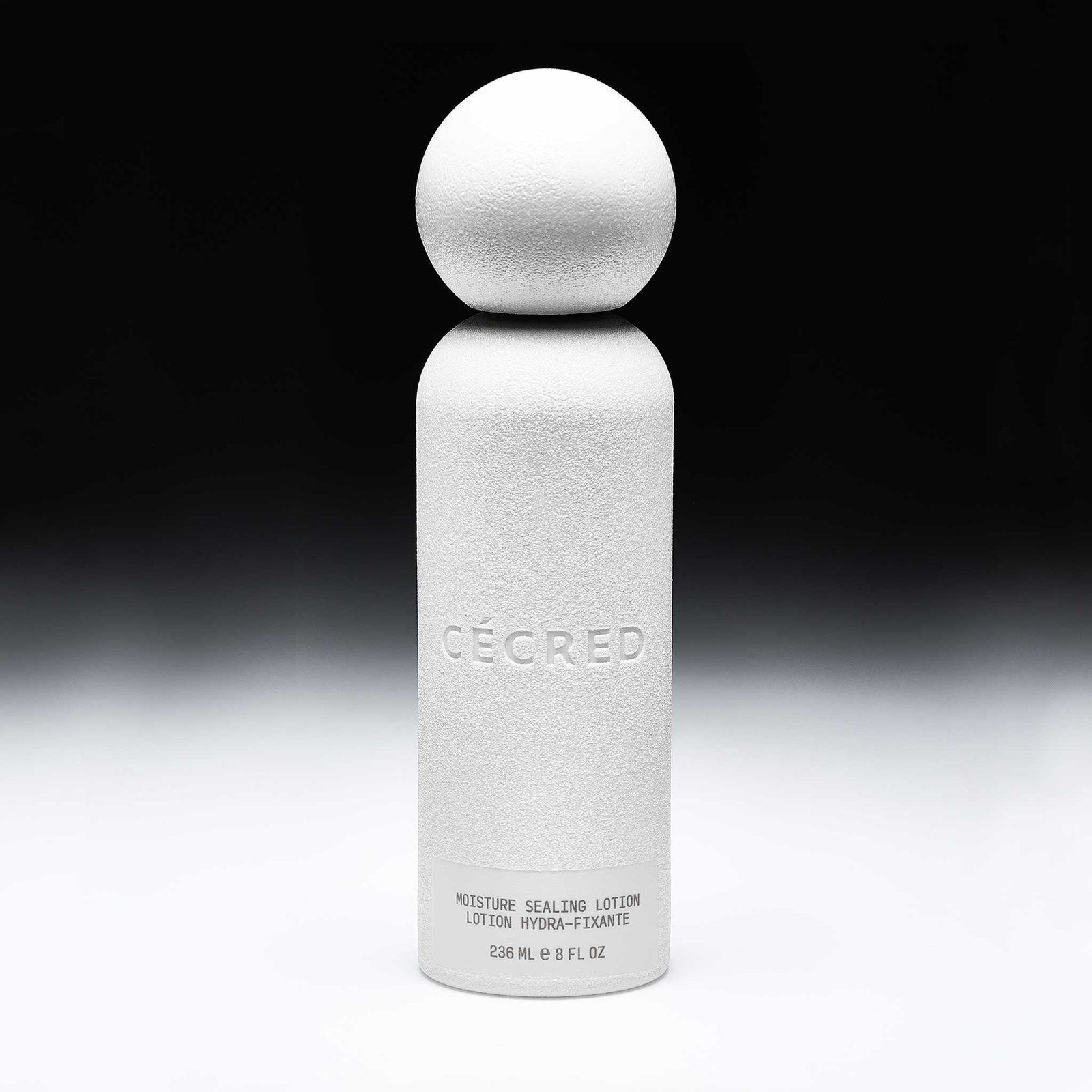 Cécred Moisture Sealing Lotion shown in full against a black and white background, spotlighting its unique round cap and matte finish